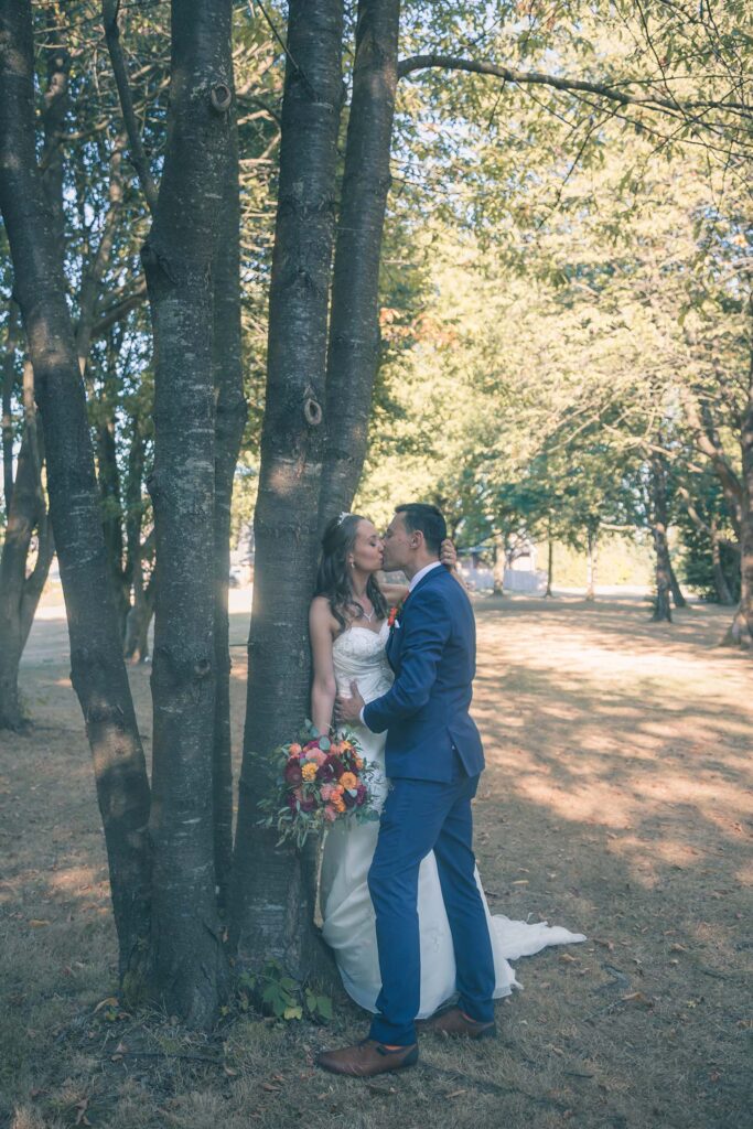 Under the tree of love: newlyweds share a intimate and passionate kiss beneath the branches, surrounded by nature's beauty, on their unforgettable wedding day